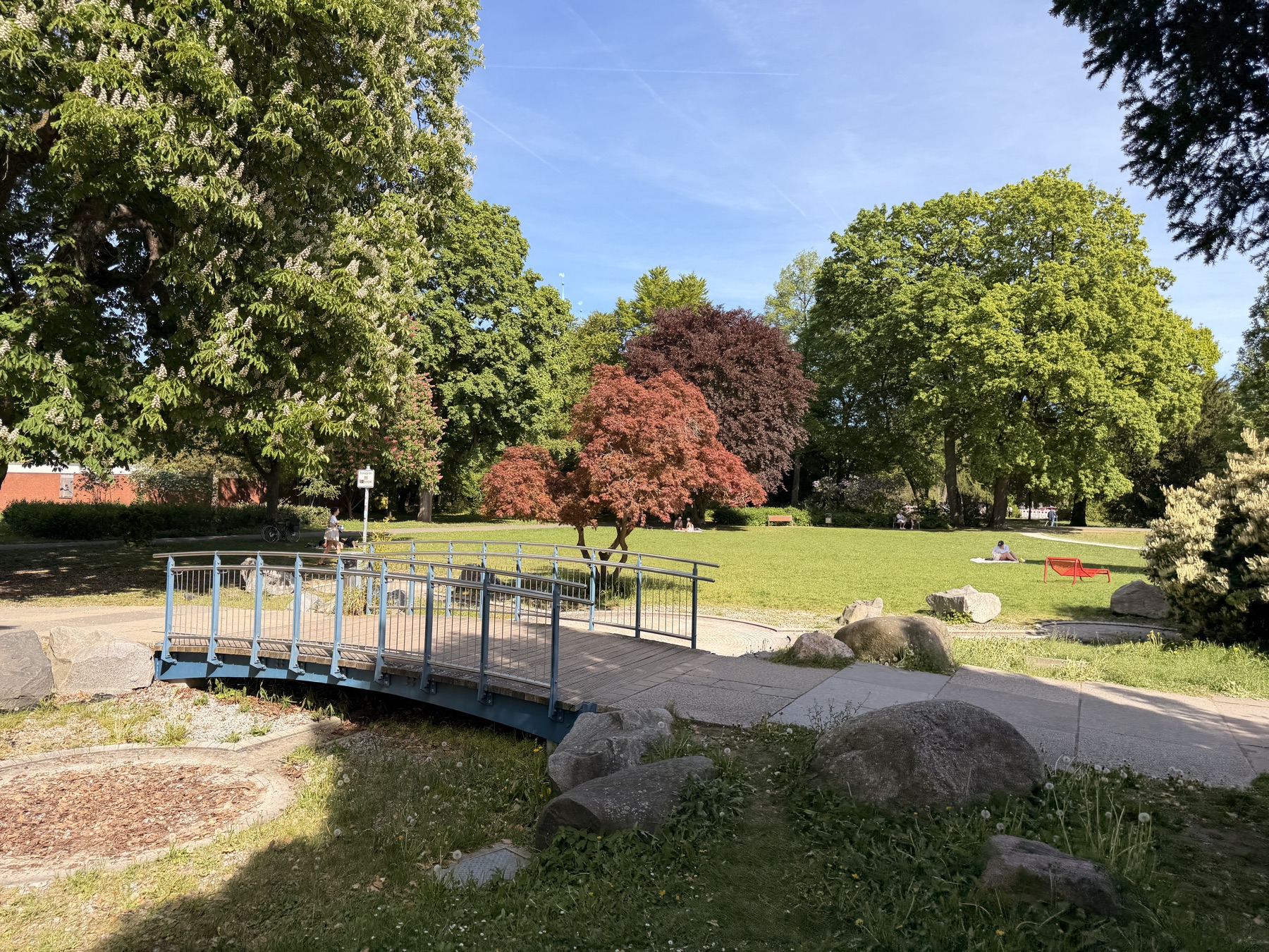 Kleine Brücke zwischen Wiesen und Bäumen im Stadtpark